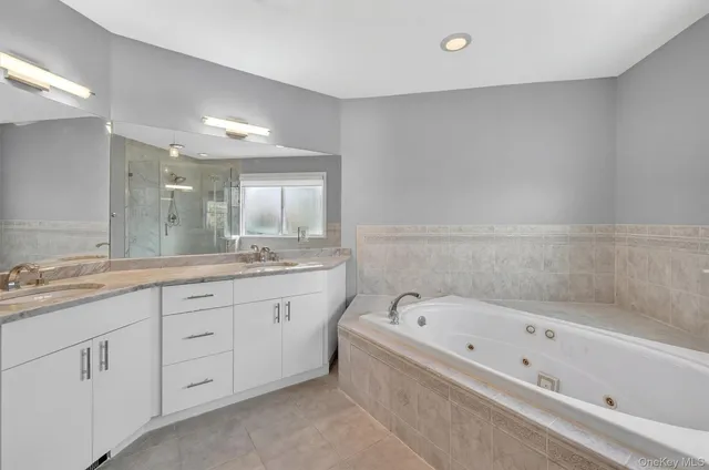 a bathroom with a bathtub a double vanity sink and mirror