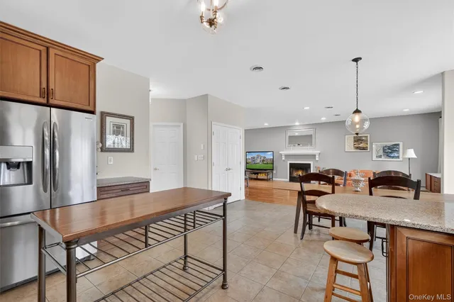a kitchen with stainless steel appliances granite countertop a stove a refrigerator a kitchen island a dining table and chairs with wooden floor