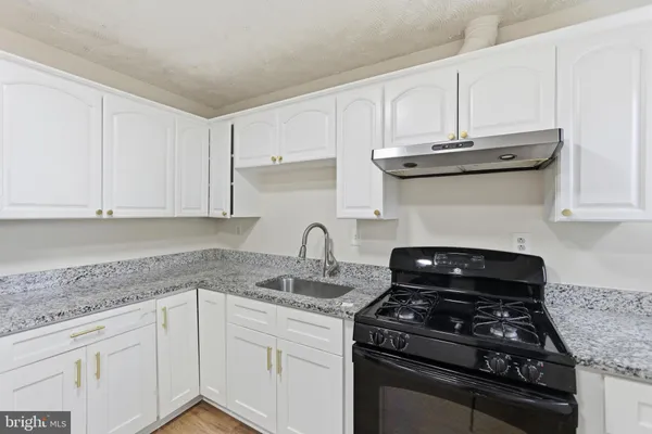 a kitchen with granite countertop white cabinets and black appliances