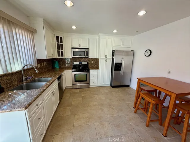 a kitchen with stainless steel appliances granite countertop a refrigerator and a stove top oven