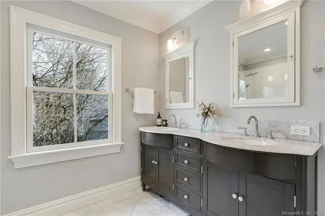 a bathroom with a double vanity sink and mirror with window