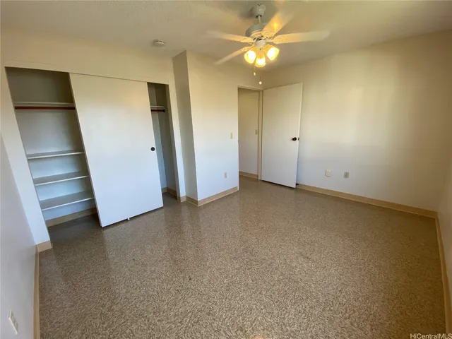 an empty room with a ceiling fan and window