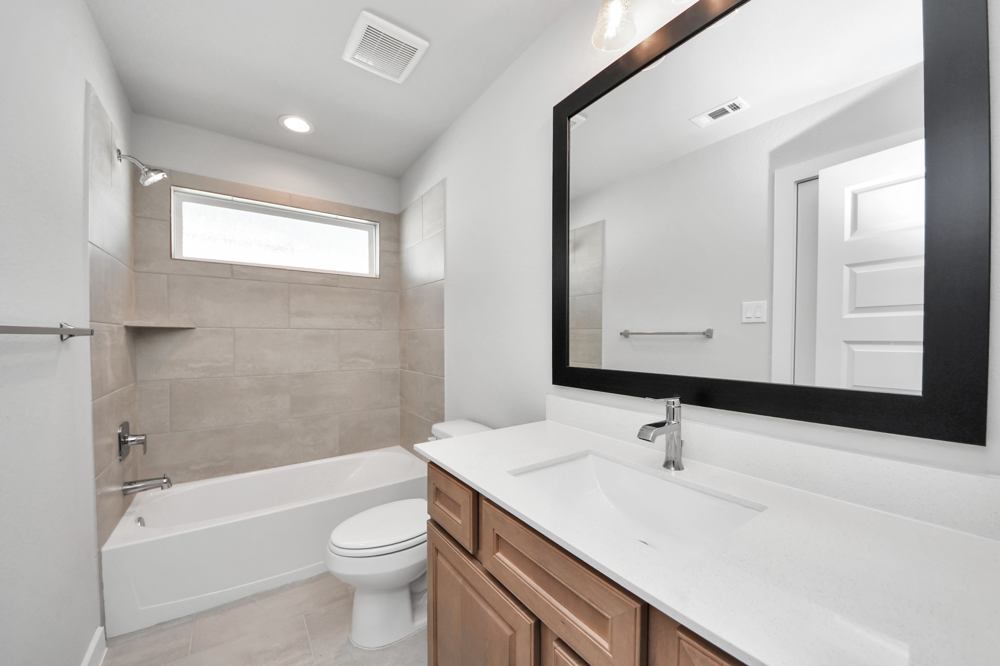 3102 Native Spg Drive Spring, TX 77373 - Photo 29 of 40 Secondary bath features tile flooring, bath/shower combo with tile surround, light stained wood cabinets, beautiful light countertop. Sample photo of completed home with similar floor plan. Actual colors and selections may vary.