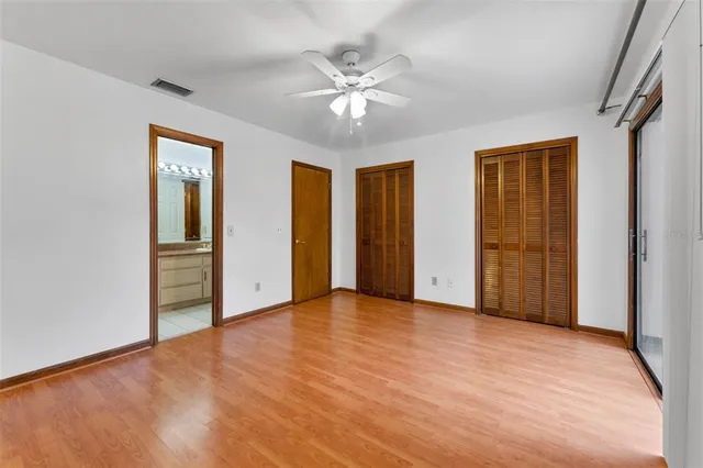 a view of an empty room with a ceiling fan and windows