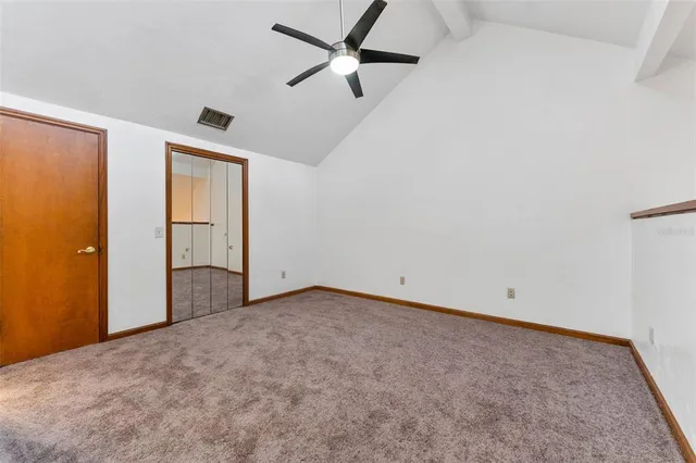 an empty room with closet and a chandelier fan