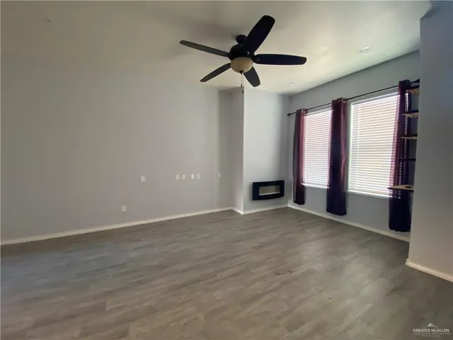 an empty room with ceiling fan and windows