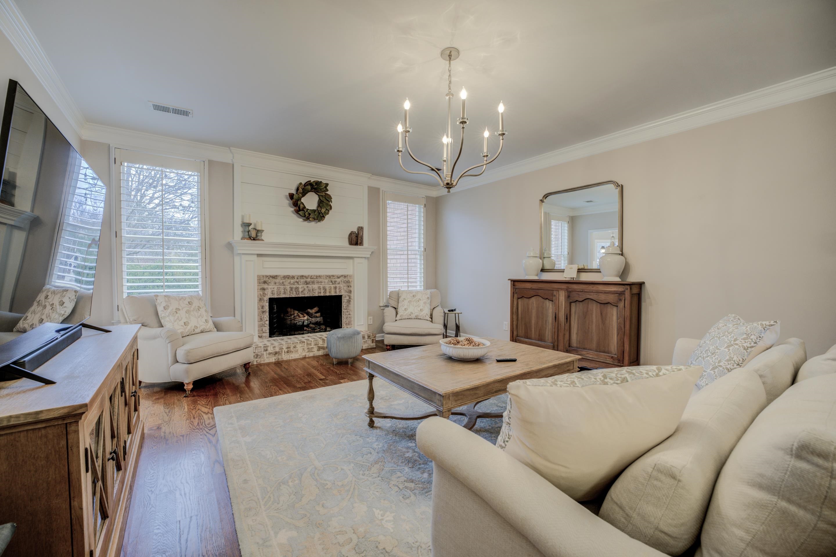 1594 John Ridge Drive Collierville, TN 38017 - Photo 6 of 29 Living room featuring crown molding, a fireplace, wood-type flooring, and an inviting chandelier