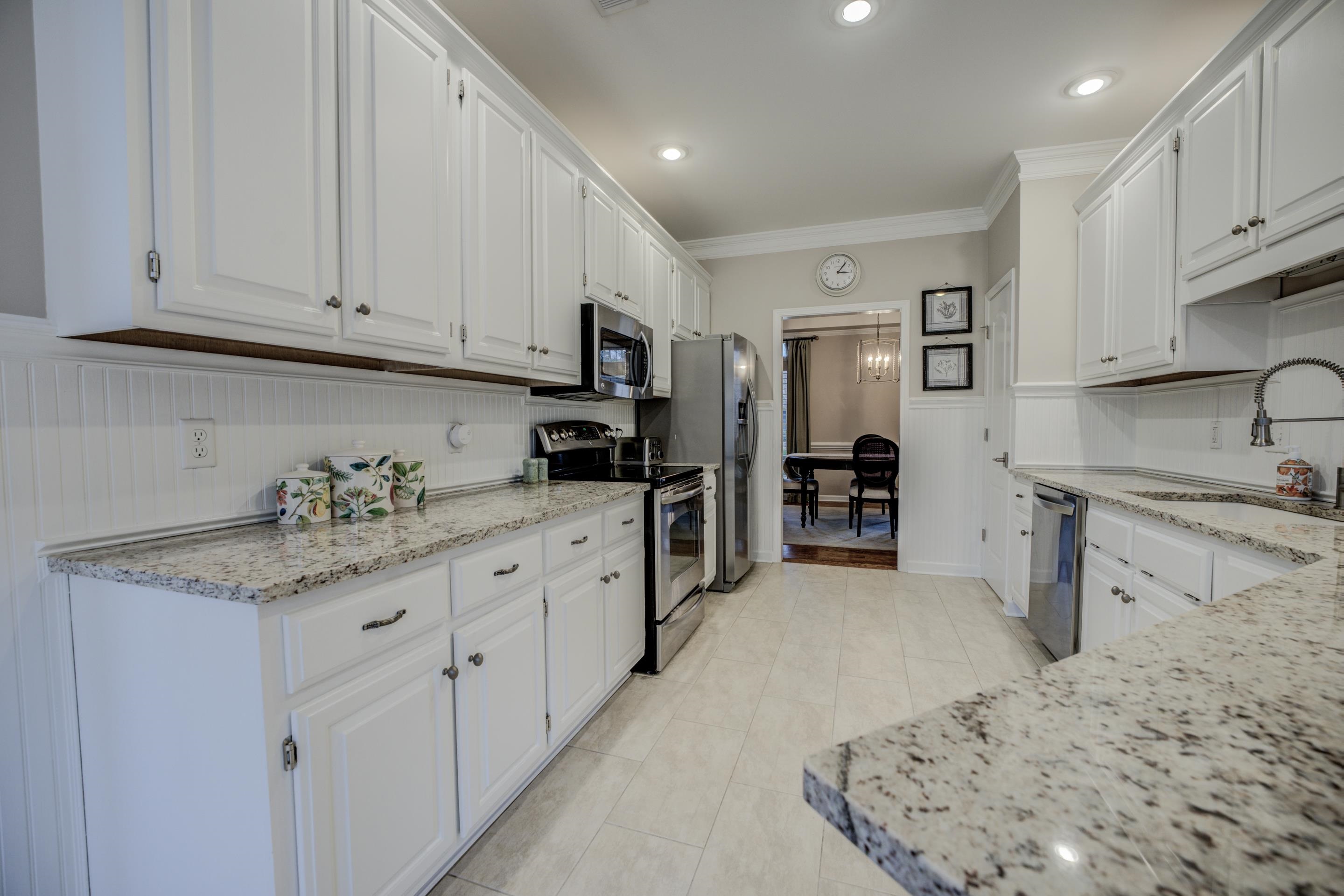 1594 John Ridge Drive Collierville, TN 38017 - Photo 8 of 29 Kitchen featuring light stone counters, stainless steel appliances, crown molding, sink, and white cabinetry