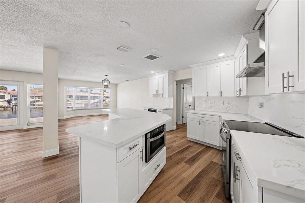 5041 Cabrilla Court New Port Richey, FL 34652 - Photo 16 of 43 a kitchen with stainless steel appliances granite countertop a sink dishwasher a refrigerator and white cabinets with wooden floor
