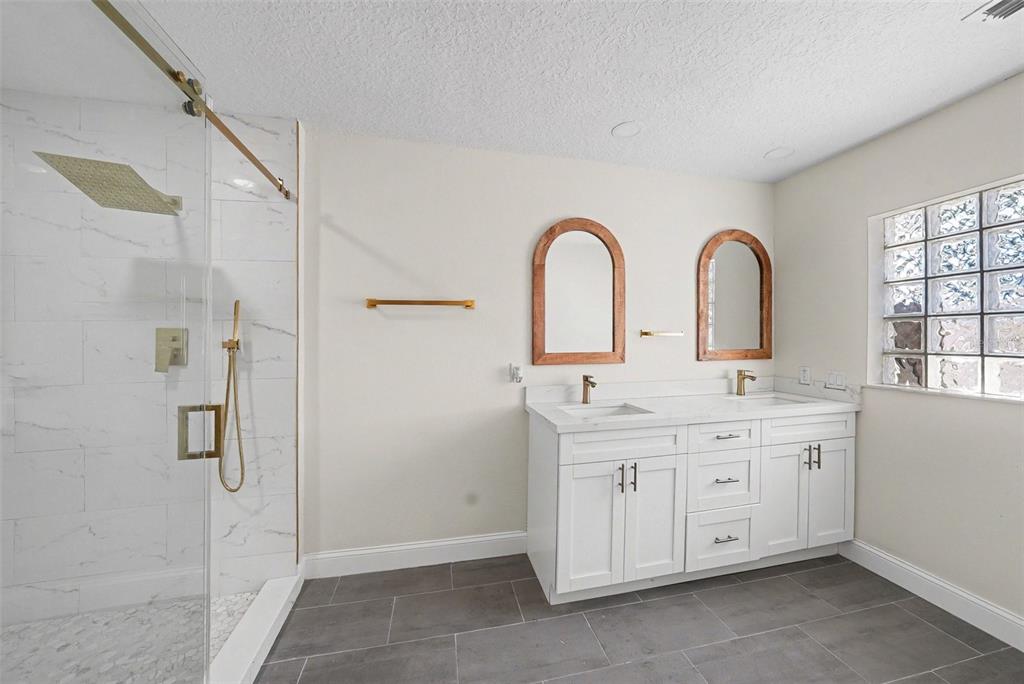 5041 Cabrilla Court New Port Richey, FL 34652 - Photo 28 of 43 a spacious bathroom with a double vanity sink a large mirror and shower