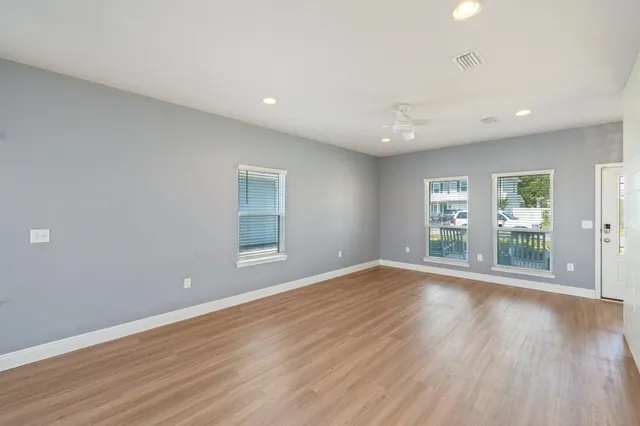 a kitchen with stainless steel appliances granite countertop a refrigerator a sink a stove a microwave and white cabinets with wooden floor