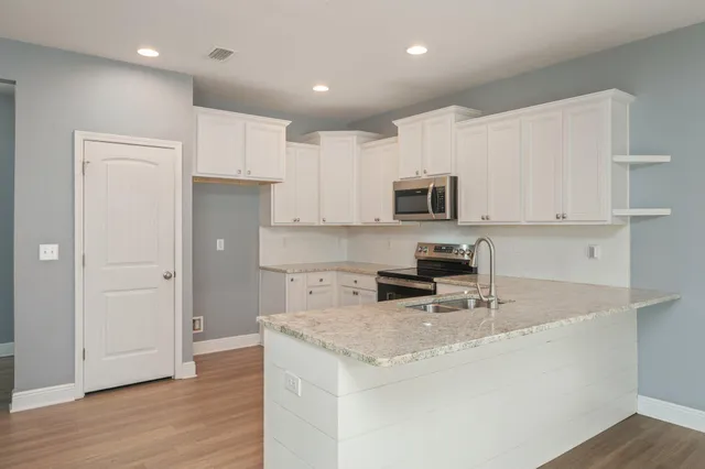 a kitchen with cabinets stainless steel appliances and wooden floor