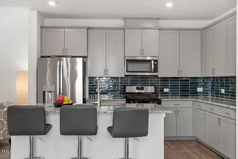 a kitchen with stainless steel appliances a stove a sink refrigerator and white cabinets