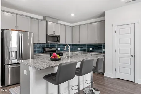 a kitchen with stainless steel appliances granite countertop a refrigerator and a stove top oven