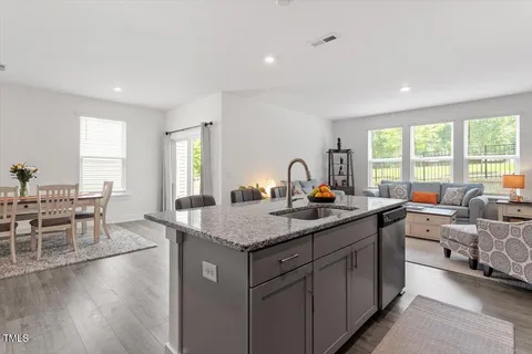 a dining hall with stainless steel appliances granite countertop a coffee table and chairs in it