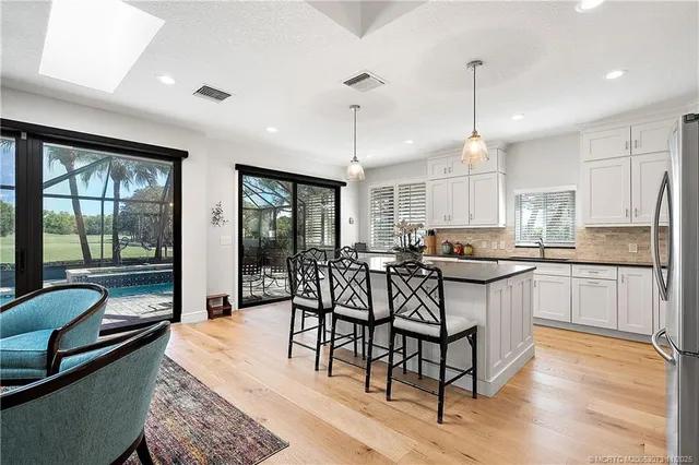 a kitchen with granite countertop a stove a sink a dining table and chairs with wooden floor