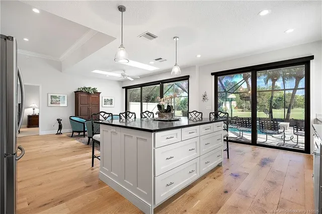 a kitchen with stainless steel appliances kitchen island granite countertop a table chairs sink and cabinets