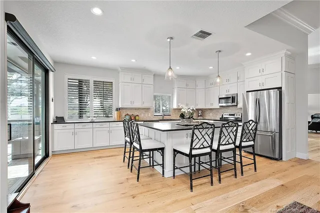 a kitchen with granite countertop white cabinets white appliances a sink and a window