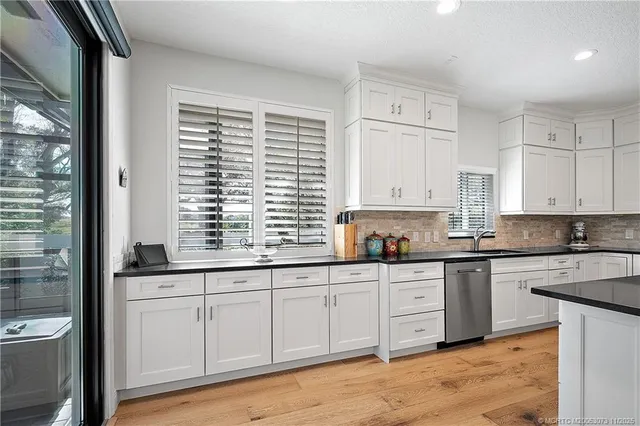 a kitchen with granite countertop white cabinets white appliances and a wide window