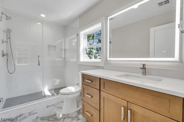 a bathroom with a granite countertop sink a toilet and a shower