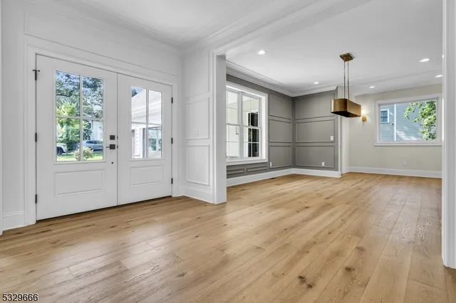 an empty room with wooden floor cabinet and windows