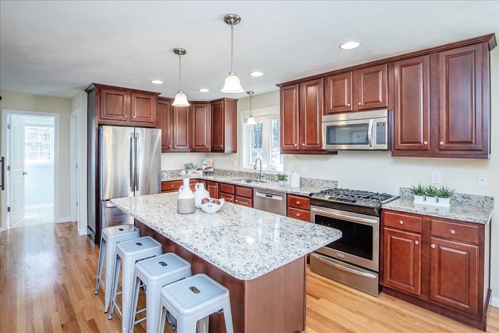 294 River Street Billerica, MA 01821 - Photo 12 of 42 a kitchen with stainless steel appliances granite countertop a refrigerator a stove a sink dishwasher and wooden cabinets with wooden floor
