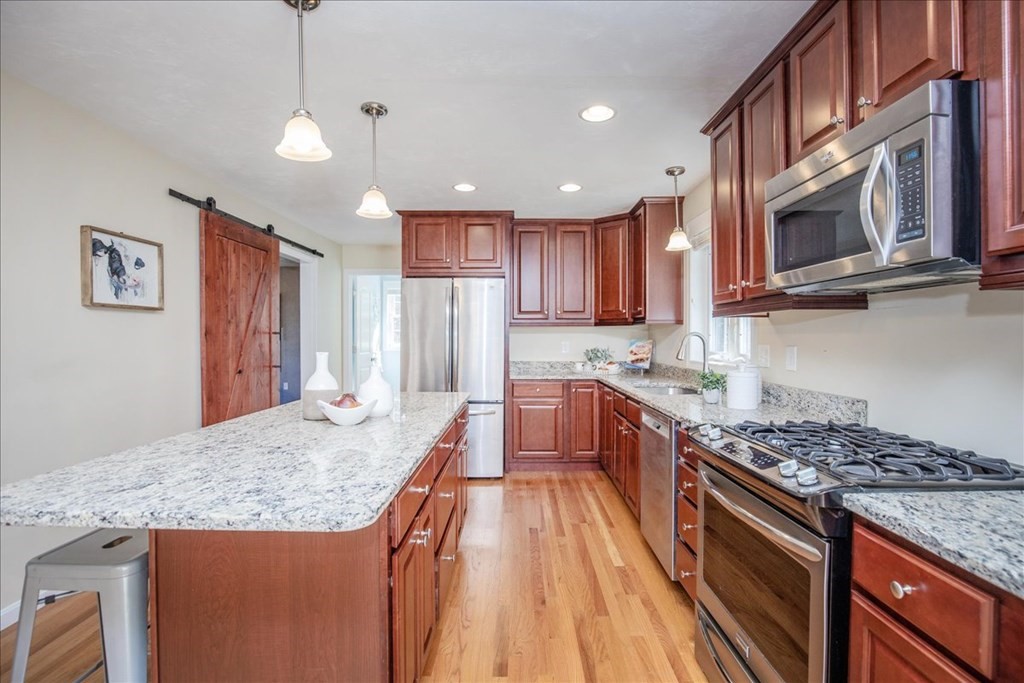 294 River Street Billerica, MA 01821 - Photo 16 of 42 a kitchen with stainless steel appliances granite countertop a stove top oven a sink dishwasher and a refrigerator with wooden cabinets