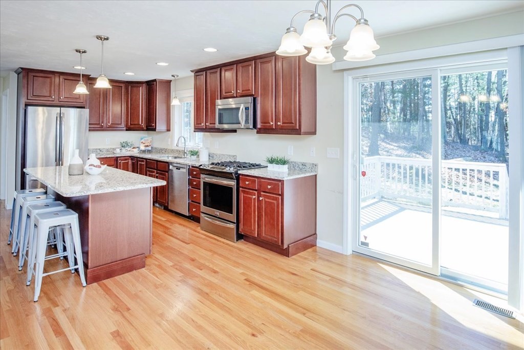 294 River Street Billerica, MA 01821 - Photo 17 of 42 a kitchen with stainless steel appliances granite countertop a stove top oven a sink dishwasher a dining table and chairs with wooden floor