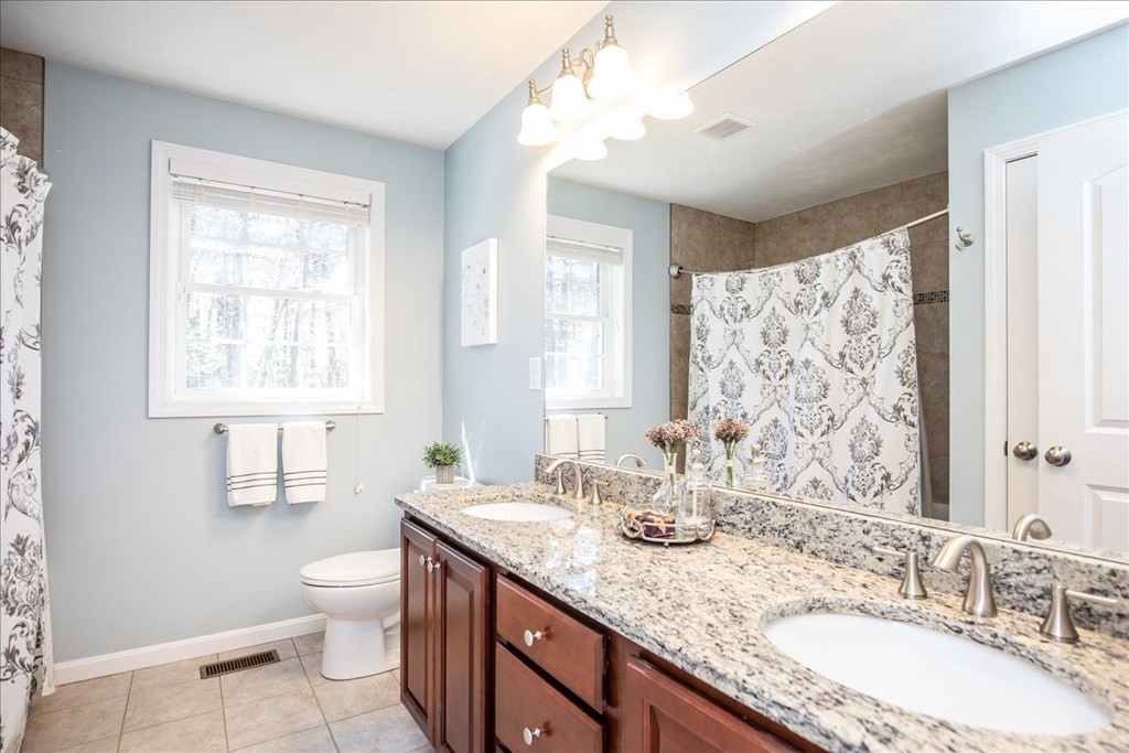 294 River Street Billerica, MA 01821 - Photo 28 of 42 a bathroom with a granite countertop double vanity sink a mirror and a toilet