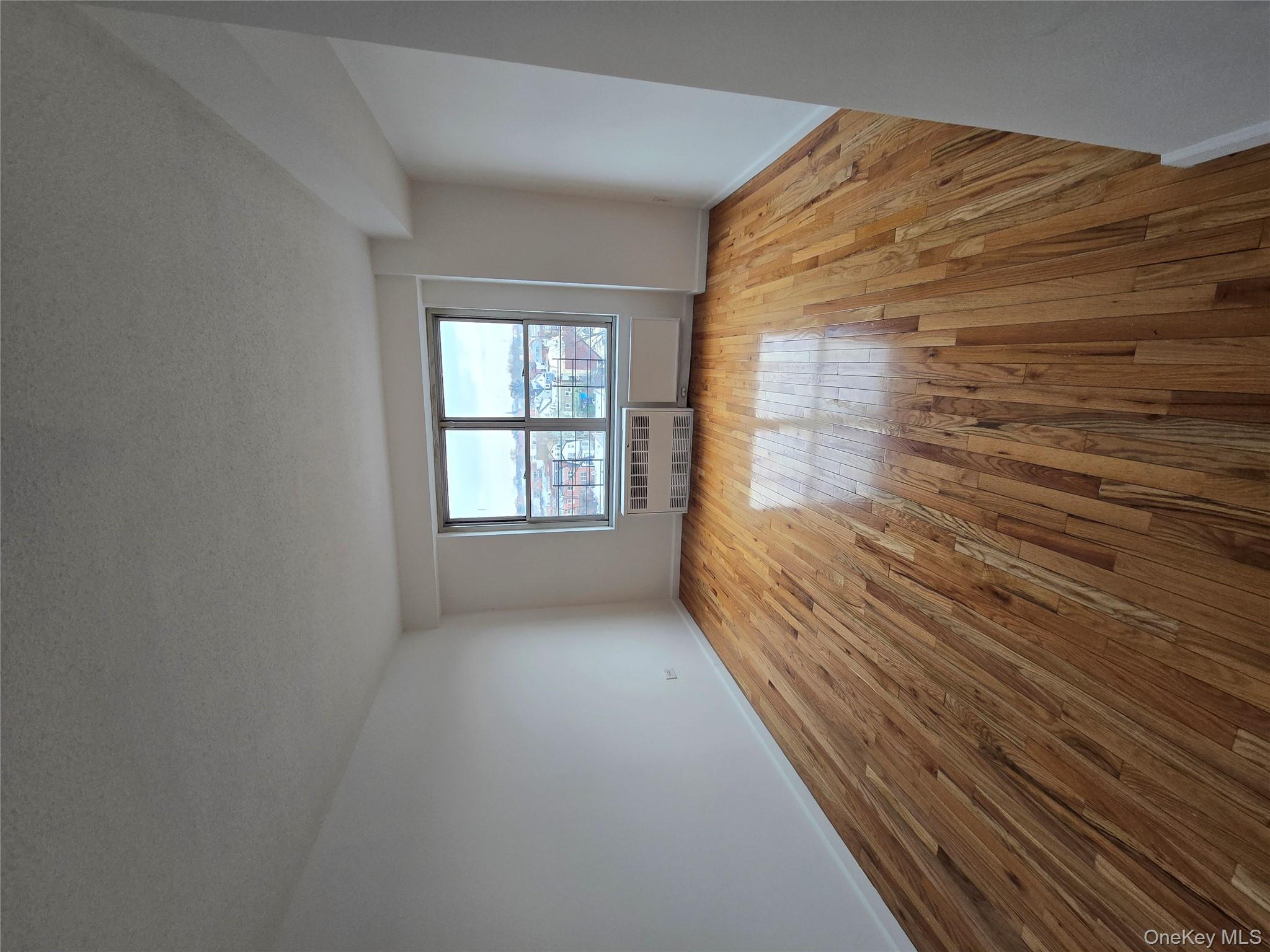 34-12 113th Street, Unit 7L Queens, NY 11368 - Photo 3 of 9 an empty room with wooden floor and windows