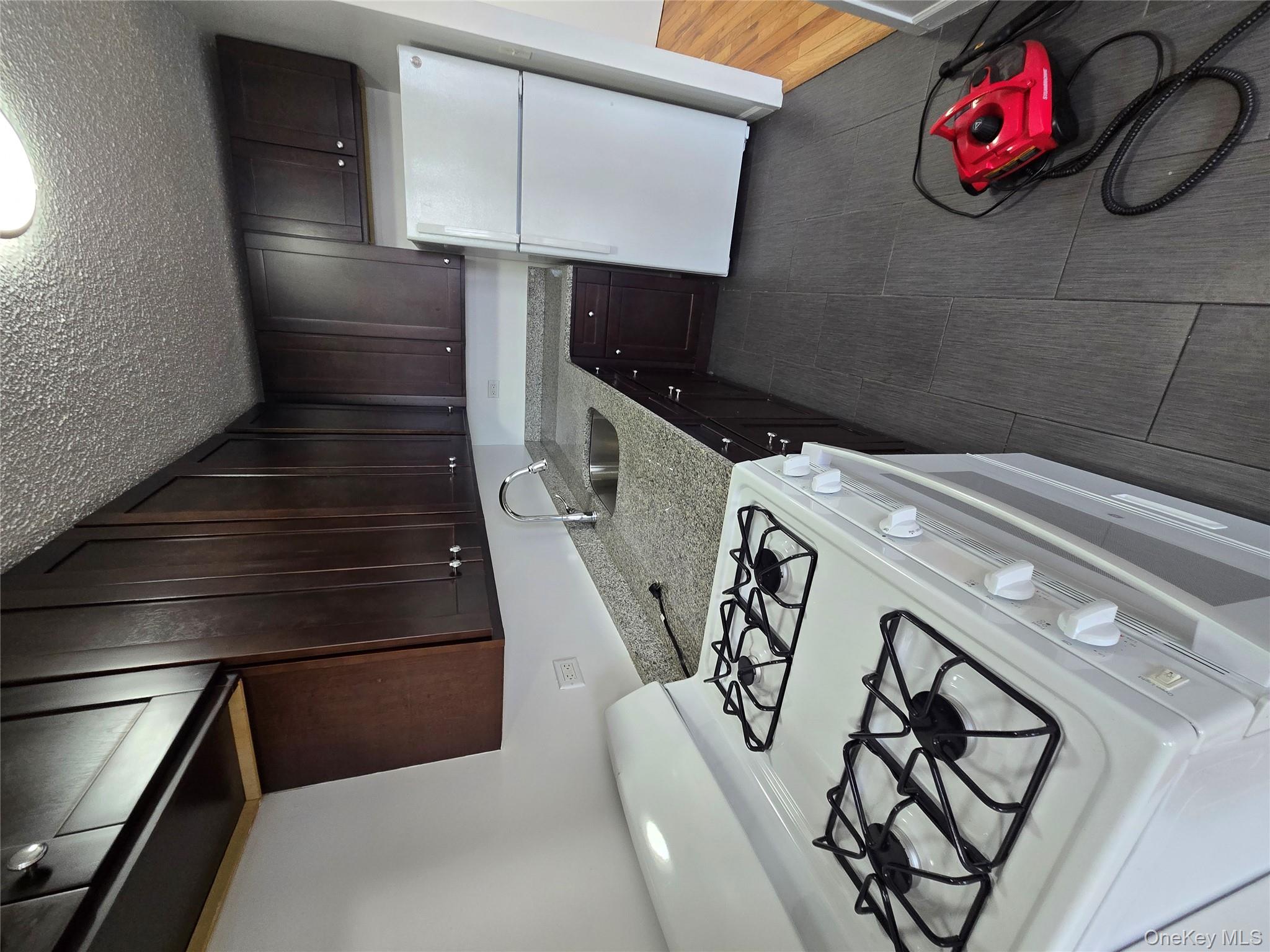 34-12 113th Street, Unit 7L Queens, NY 11368 - Photo 4 of 9 a kitchen with granite countertop a stove sink and cabinets