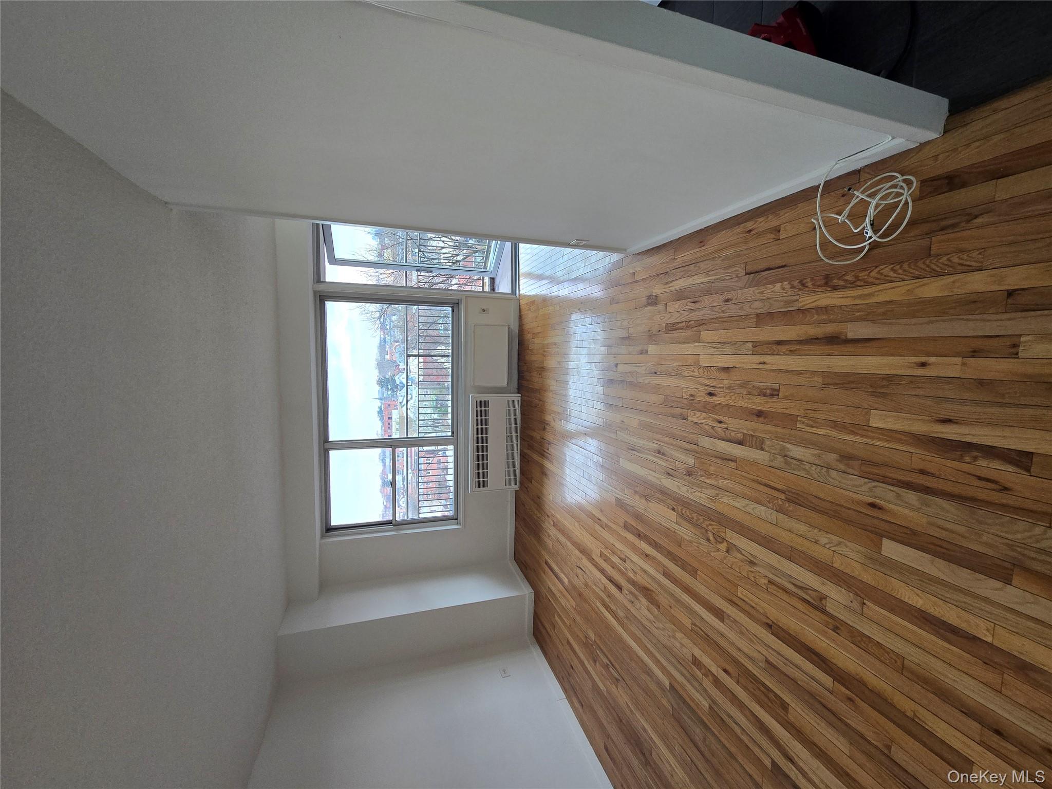 34-12 113th Street, Unit 7L Queens, NY 11368 - Photo 6 of 9 wooden floor in an empty room with a window