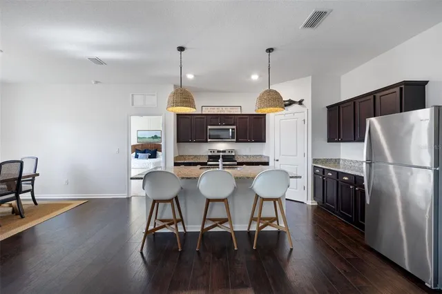 a kitchen with stainless steel appliances a dining table chairs refrigerator and sink