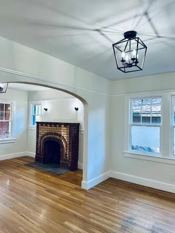 an empty room with wooden floor a fireplace and chandelier