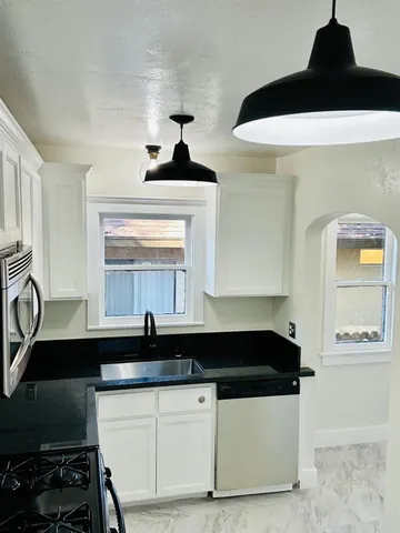 a close view of a sink a large mirror and cabinets