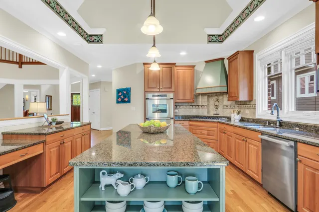 a kitchen with stainless steel appliances granite countertop a sink a stove and a wooden cabinets