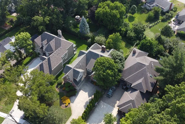 an aerial view of residential house with outdoor space and trees all around