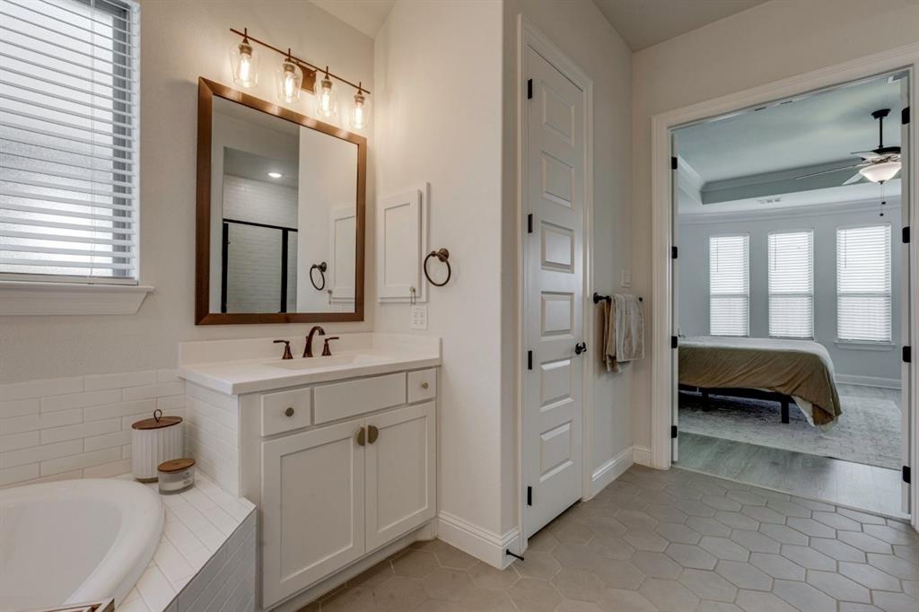 9613 Boulder Pt Road Oak Point, TX 75068 - Photo 19 of 28 Bathroom featuring a white vanity with bronze hardware, a framed mirror, and a four-light fixture
