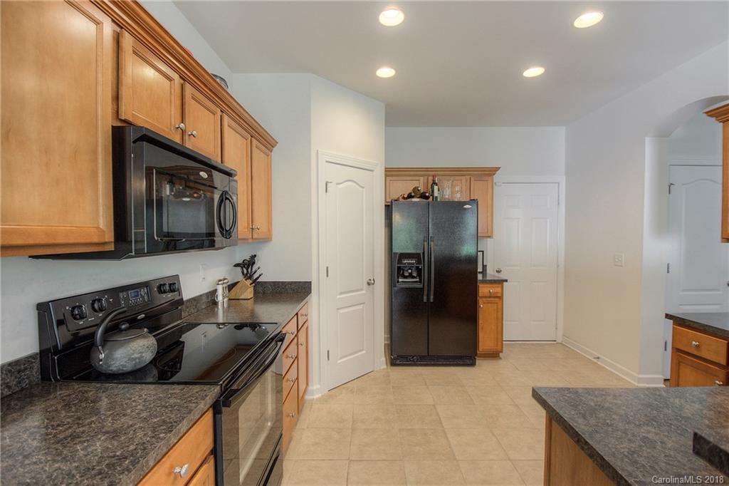 6831 Maricopa Road Charlotte, NC 28277 - Photo 12 of 23 a kitchen with stainless steel appliances granite countertop a refrigerator a stove and a sink with wooden cabinets