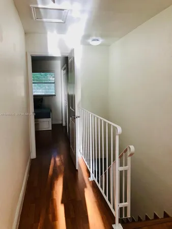 a view of a hallway with wooden floor and staircase
