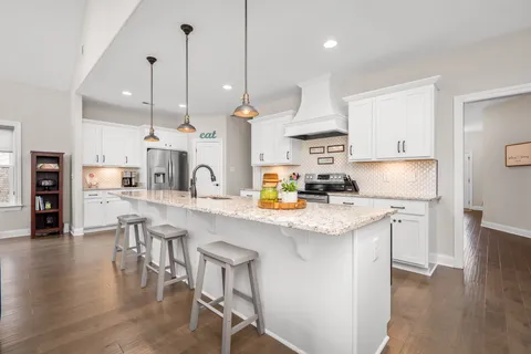 a open kitchen with stainless steel appliances granite countertop a sink a stove a refrigerator and island with wooden floor