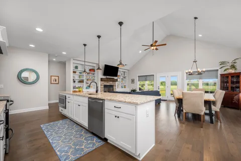 a dining room with wooden floor a chandelier a glass table and chairs