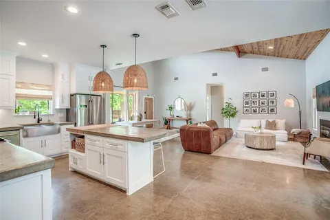 a large kitchen with stainless steel appliances kitchen island granite countertop a sink a stove a dining table and chairs