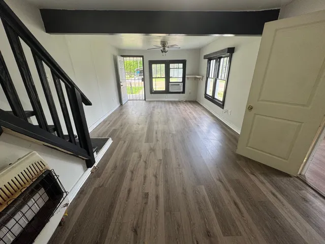 a view of an empty room with wooden floor and windows