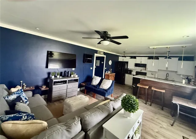 a living room with furniture a flat screen tv and kitchen view