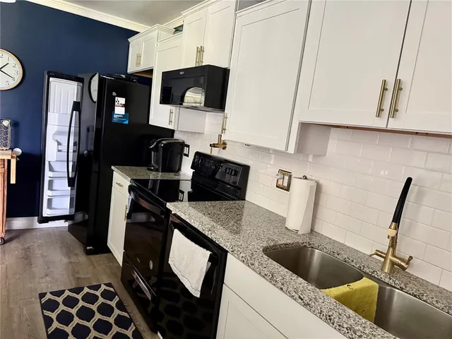 a kitchen with a sink a stove and a microwave with granite countertops