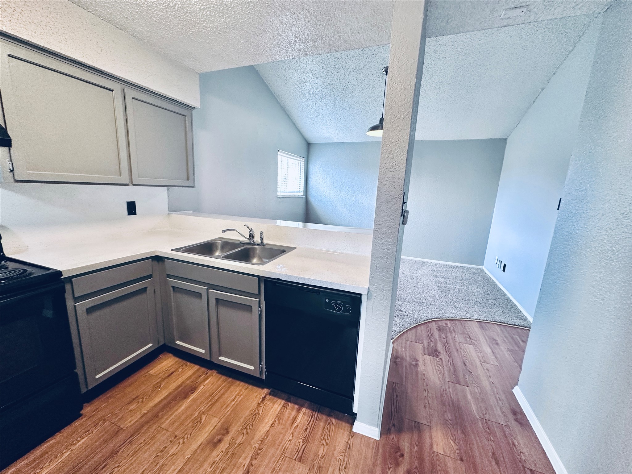 3702 South 2nd Street, Unit 321 Austin, TX 78704 - Photo 6 of 13 Kitchen with gray cabinets, black appliances, a textured wall, light wood-style floors, and a peninsula