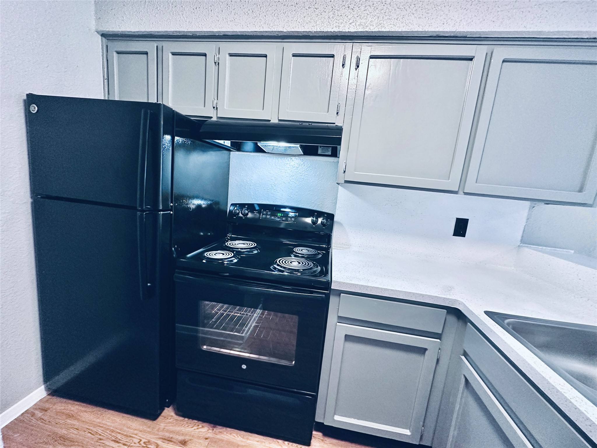 3702 South 2nd Street, Unit 321 Austin, TX 78704 - Photo 8 of 13 Kitchen featuring electric range, gray cabinetry, light stone counters, a textured wall, and light wood-style floors