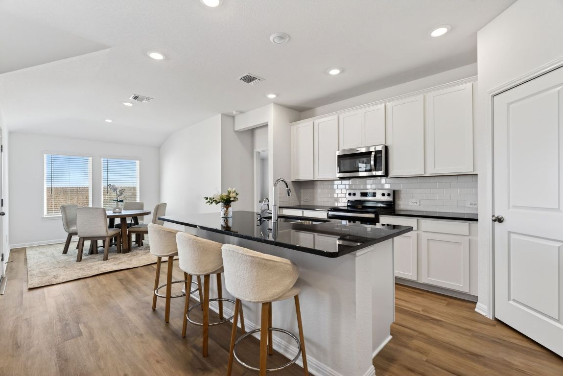 120 Honey Bee Road Jarrell, TX 76537 - Photo 5 of 20 a kitchen with stainless steel appliances granite countertop a stove top oven a sink dishwasher a dining table and chairs with wooden floor