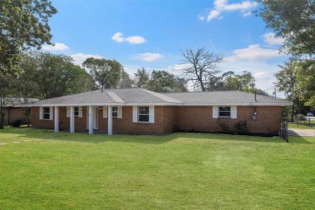 a view of a house next to a big yard with plants and trees
